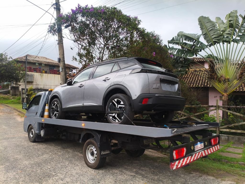 SUV cinza preso à plataforma para transporte de veículos